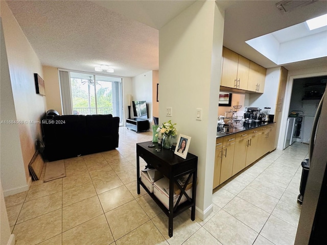 kitchen with a skylight, a textured ceiling, cream cabinets, and light tile patterned flooring