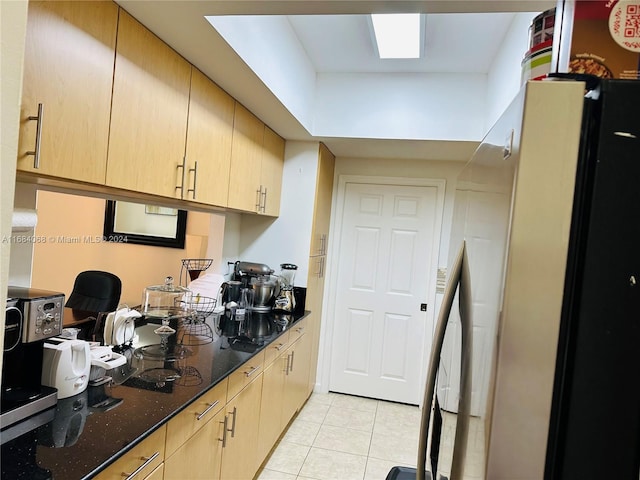 kitchen with dark stone counters, light brown cabinetry, and light tile patterned floors