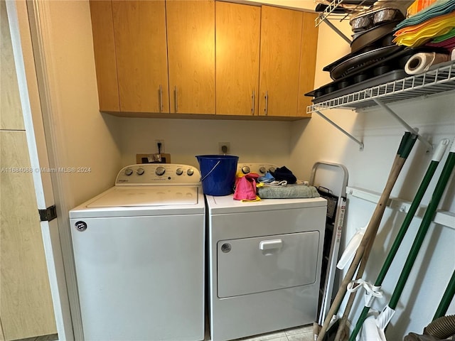 clothes washing area featuring cabinets and separate washer and dryer