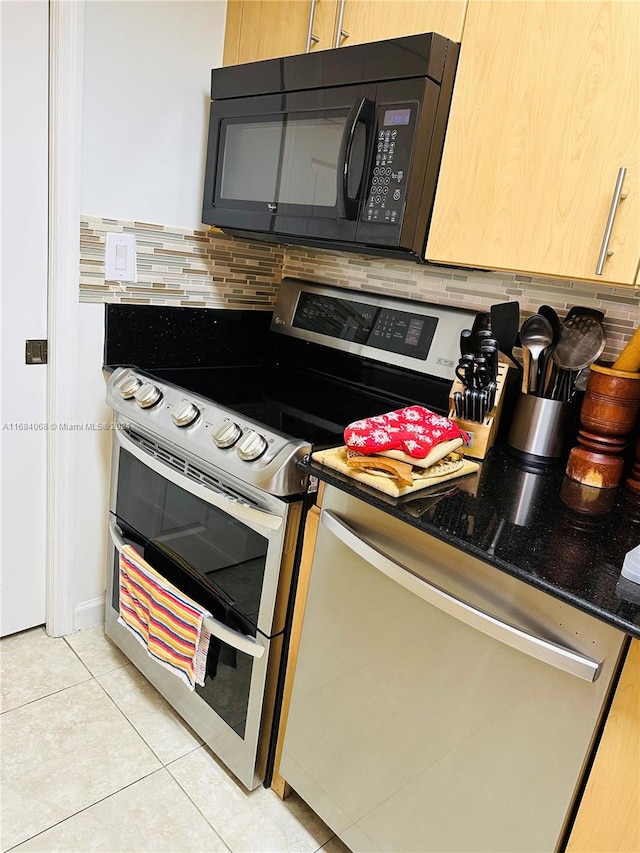 kitchen featuring dark stone counters, tasteful backsplash, range with two ovens, and light tile patterned floors