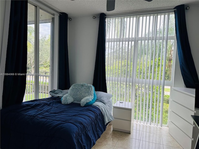 tiled bedroom with ceiling fan, access to exterior, multiple windows, and a textured ceiling