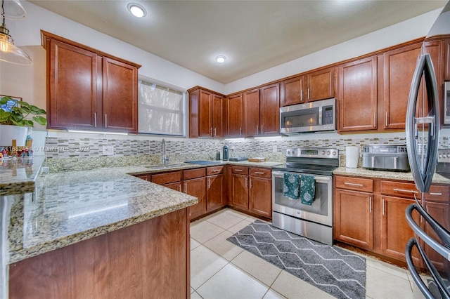 kitchen featuring light stone counters, backsplash, appliances with stainless steel finishes, sink, and decorative light fixtures