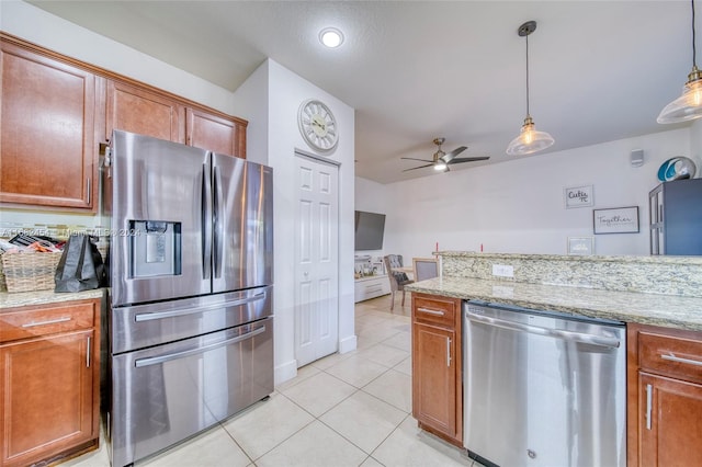 kitchen featuring hanging light fixtures, ceiling fan, appliances with stainless steel finishes, light tile patterned flooring, and light stone counters