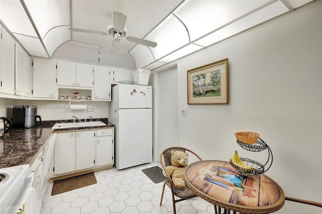 kitchen featuring white appliances, sink, ceiling fan, vaulted ceiling, and white cabinets