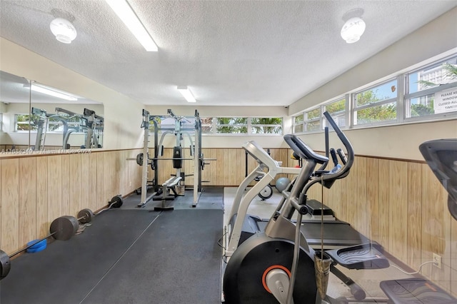 exercise room featuring a textured ceiling and wood walls