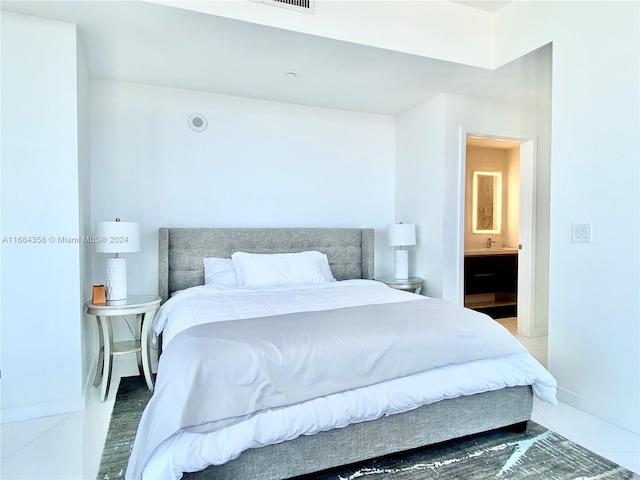 bedroom with ensuite bath and light tile patterned flooring