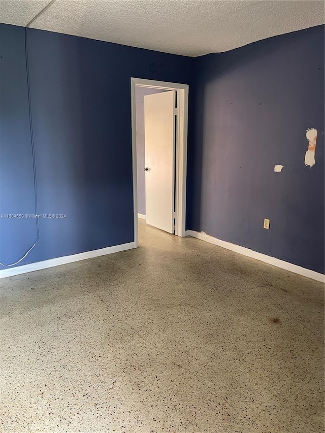 spare room with baseboards, a textured ceiling, and speckled floor