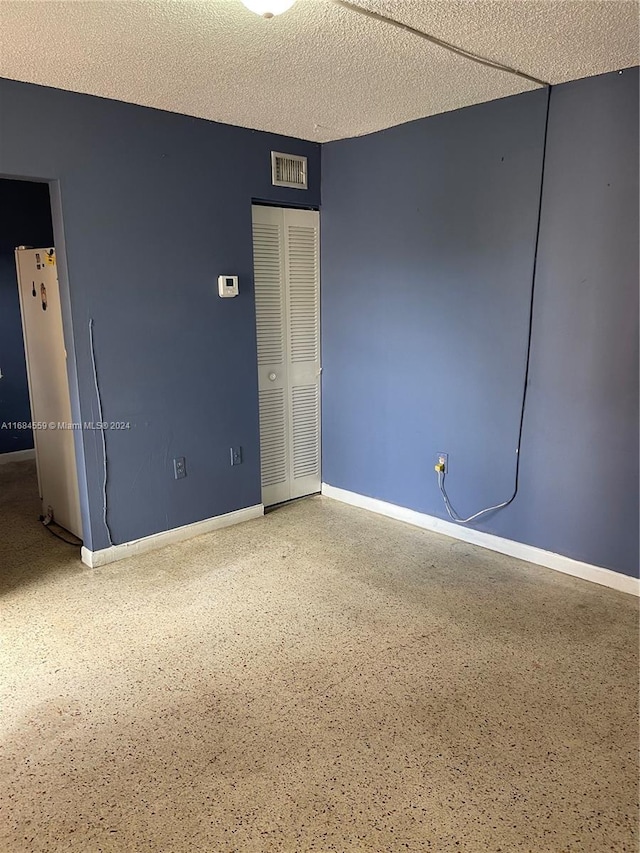 unfurnished room featuring baseboards, a textured ceiling, visible vents, and speckled floor