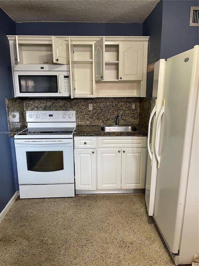 kitchen featuring white appliances, sink, a textured ceiling, white cabinetry, and dark stone counters