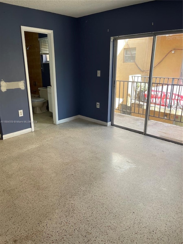 spare room with baseboards and speckled floor