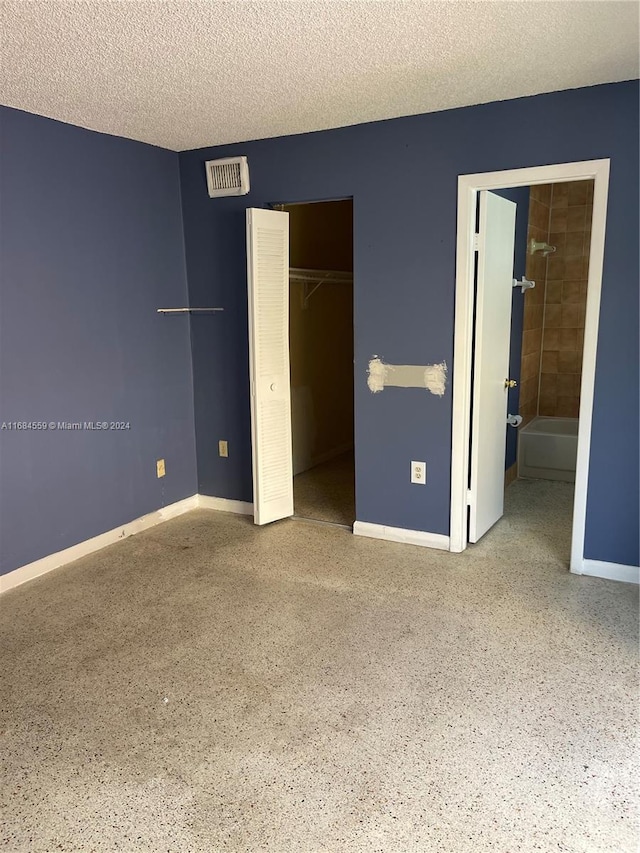 unfurnished bedroom featuring a textured ceiling and connected bathroom