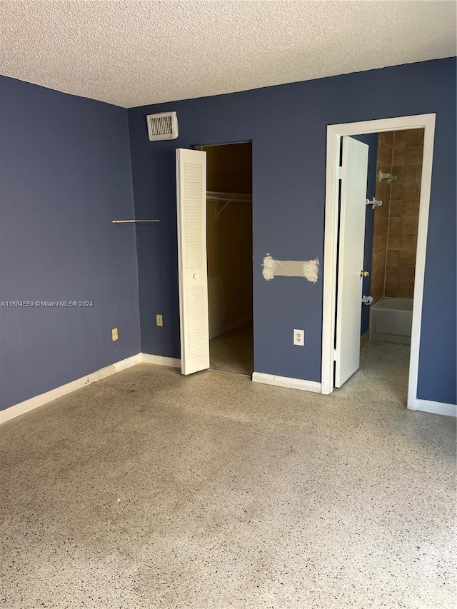 unfurnished bedroom featuring a textured ceiling, visible vents, speckled floor, baseboards, and a closet