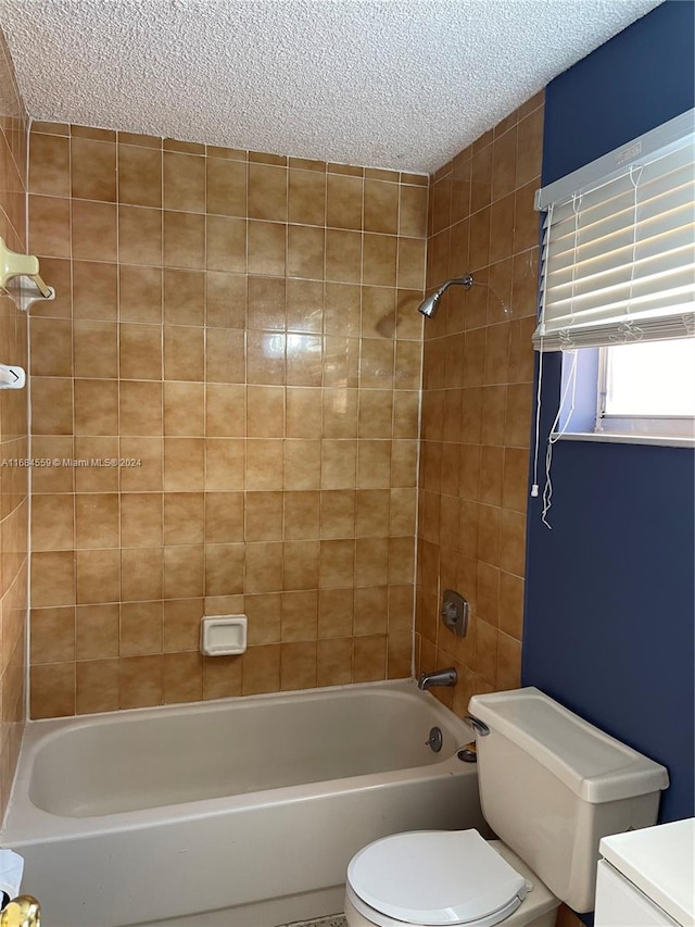 full bathroom with tiled shower / bath, vanity, a textured ceiling, and toilet