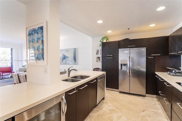 kitchen featuring dark brown cabinetry, stainless steel appliances, beverage cooler, and sink