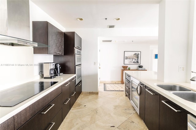 kitchen with stainless steel double oven, wall chimney range hood, dark brown cabinetry, and black electric cooktop