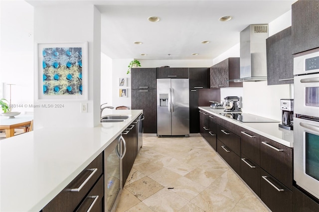 kitchen featuring dark brown cabinetry, sink, wall chimney exhaust hood, and appliances with stainless steel finishes