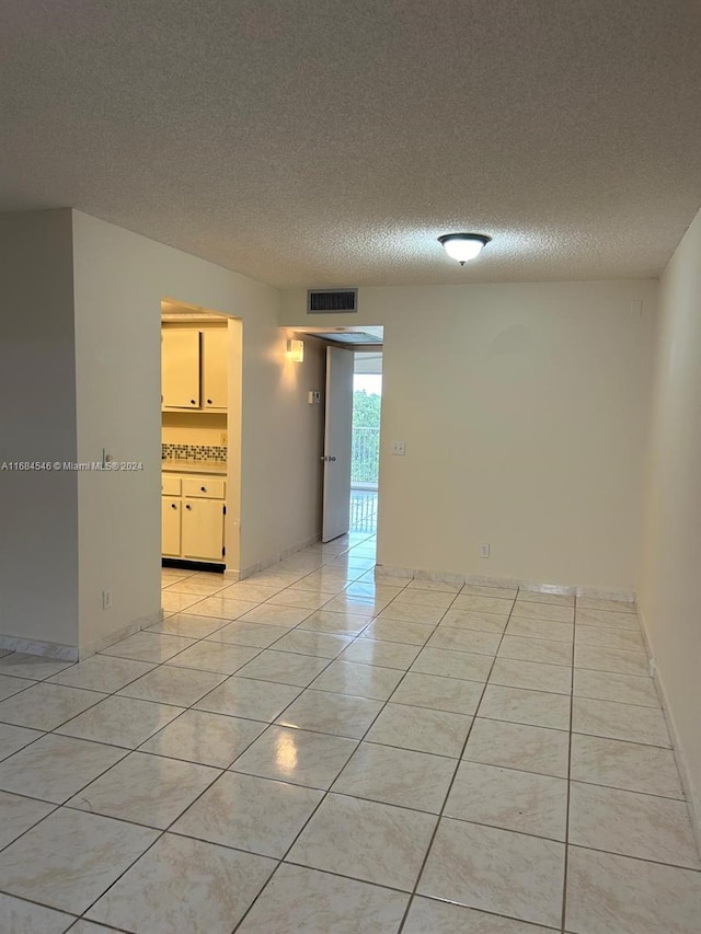 spare room featuring a textured ceiling and light tile patterned floors