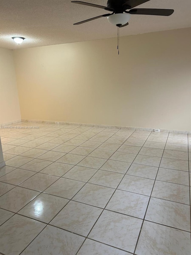 tiled empty room with a textured ceiling and ceiling fan