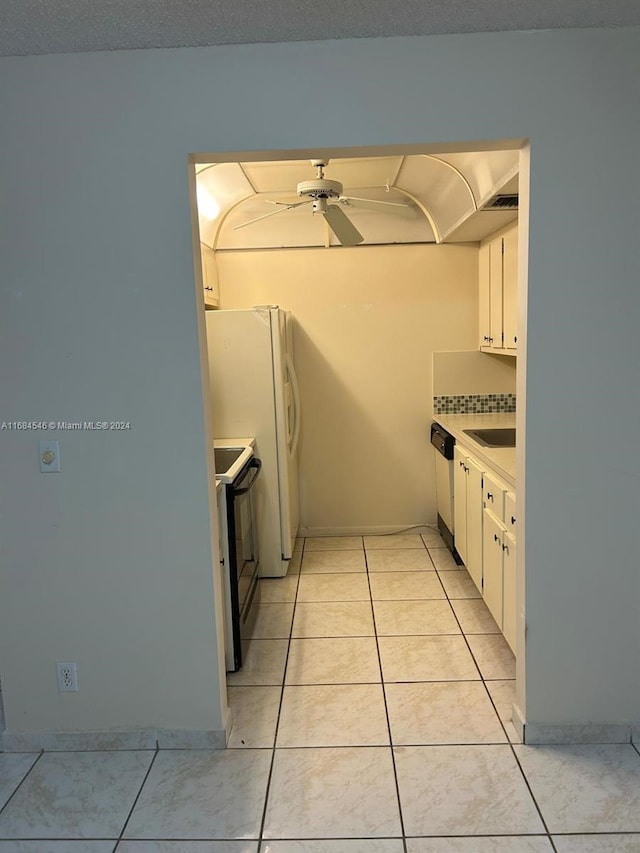 kitchen featuring white cabinetry, dishwashing machine, light tile patterned floors, and black / electric stove