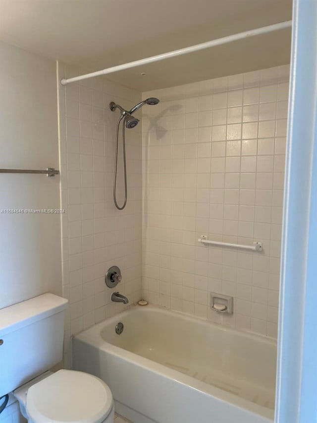 bathroom with tiled shower / bath combo and toilet