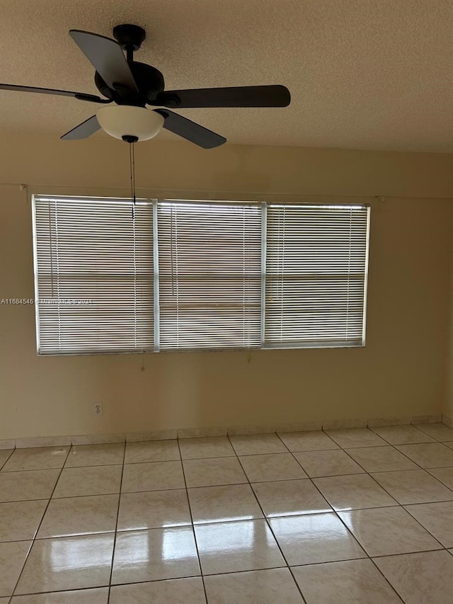 spare room with ceiling fan, a textured ceiling, and light tile patterned floors