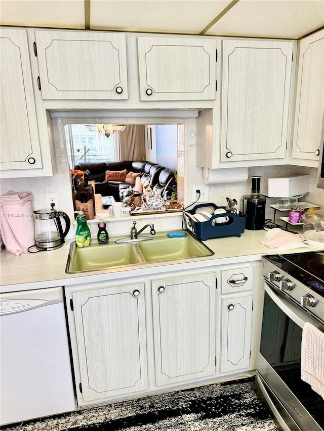 kitchen featuring white dishwasher, sink, white cabinets, and stainless steel stove