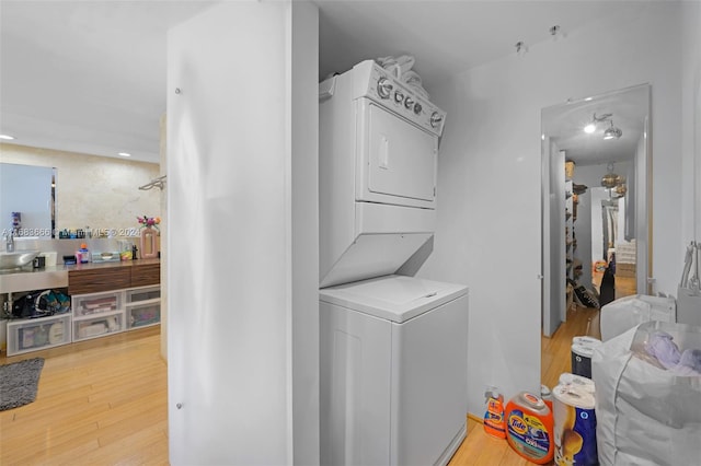 washroom with sink, light hardwood / wood-style floors, and stacked washer and dryer