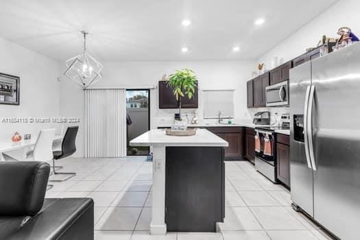 kitchen featuring light tile patterned floors, appliances with stainless steel finishes, a chandelier, a center island, and decorative light fixtures