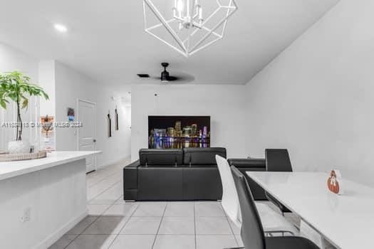 interior space with light tile patterned flooring and ceiling fan with notable chandelier