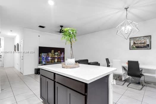 kitchen with a notable chandelier, light tile patterned floors, hanging light fixtures, and a kitchen island