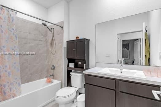 full bathroom featuring vanity, shower / bath combination with curtain, and toilet