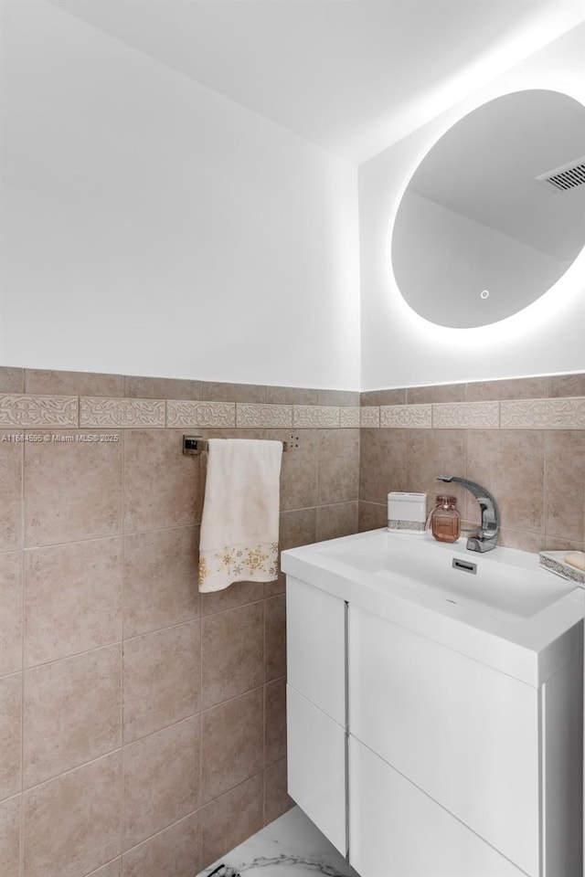 bathroom with vanity, tile walls, visible vents, wainscoting, and marble finish floor