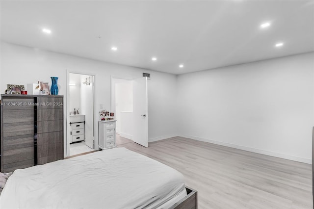 bedroom featuring connected bathroom and light hardwood / wood-style flooring