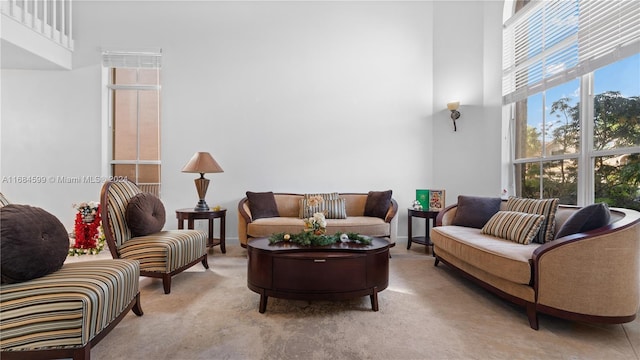 living room featuring a towering ceiling and light colored carpet