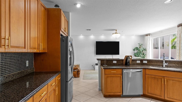 kitchen with sink, dark stone countertops, a textured ceiling, light tile patterned flooring, and appliances with stainless steel finishes