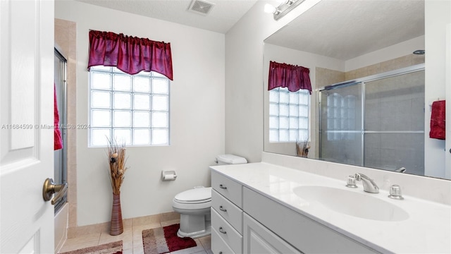 bathroom featuring toilet, a textured ceiling, tile patterned floors, and plenty of natural light