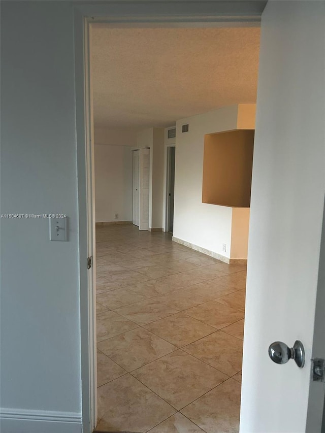 corridor featuring light tile patterned floors and a textured ceiling