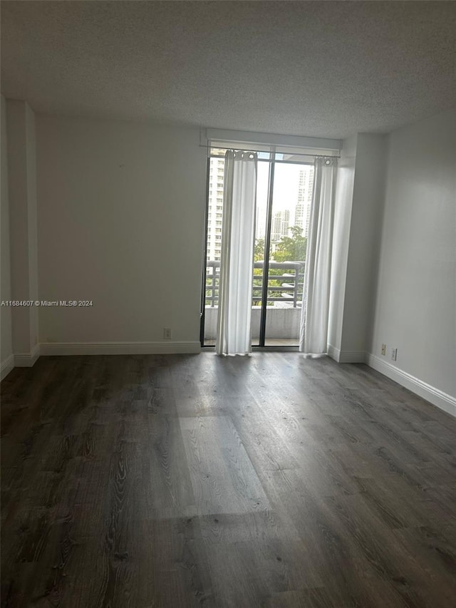 spare room with a textured ceiling and dark hardwood / wood-style flooring