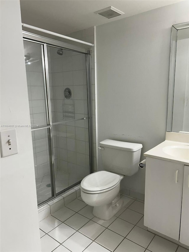 bathroom with tile patterned flooring, vanity, toilet, and a shower with door