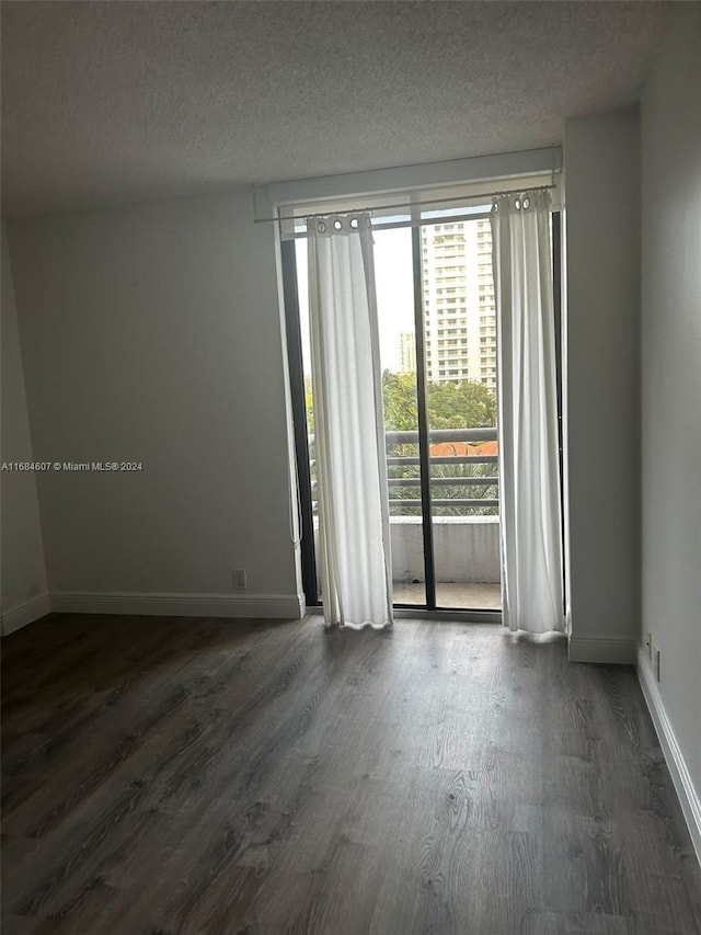 unfurnished room with dark hardwood / wood-style floors and a textured ceiling