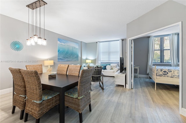 dining space featuring a textured ceiling, light hardwood / wood-style floors, and a notable chandelier