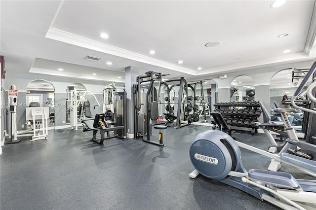 exercise room featuring a raised ceiling and ornamental molding