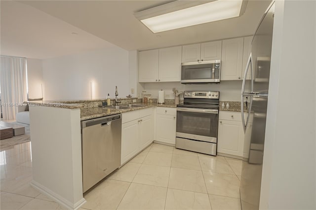 kitchen with light stone countertops, sink, kitchen peninsula, white cabinetry, and stainless steel appliances