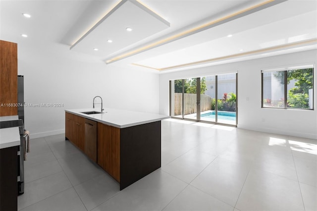 kitchen with dishwasher, sink, an island with sink, and light tile patterned floors