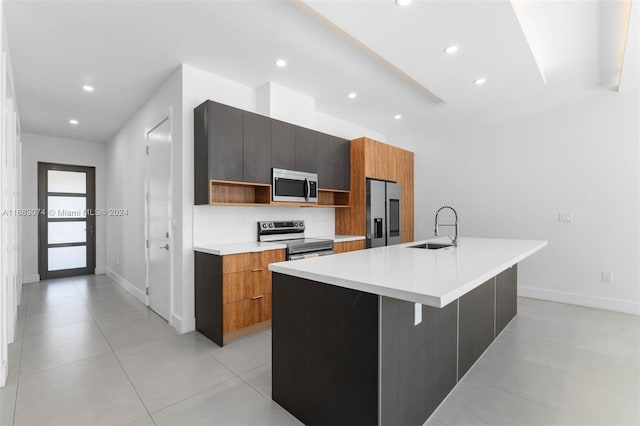 kitchen featuring a kitchen island with sink, a kitchen breakfast bar, sink, light tile patterned floors, and appliances with stainless steel finishes