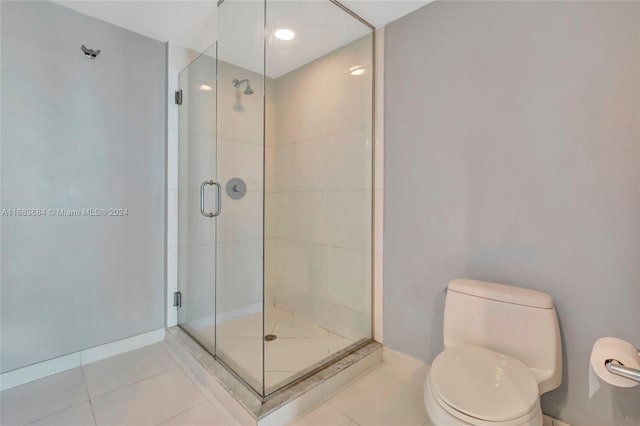 bathroom featuring toilet, tile patterned floors, and a shower with shower door