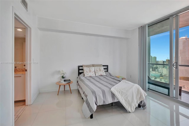 bedroom with ensuite bathroom and light tile patterned floors