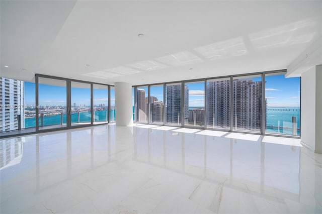 unfurnished room featuring a water view and expansive windows