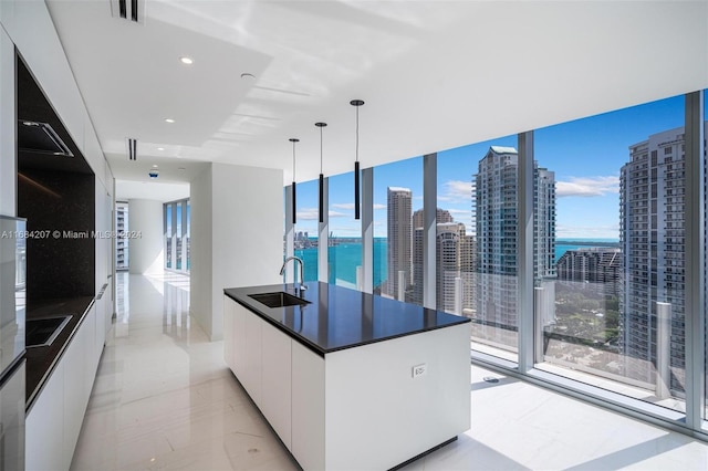 kitchen featuring a water view, sink, decorative light fixtures, and white cabinets