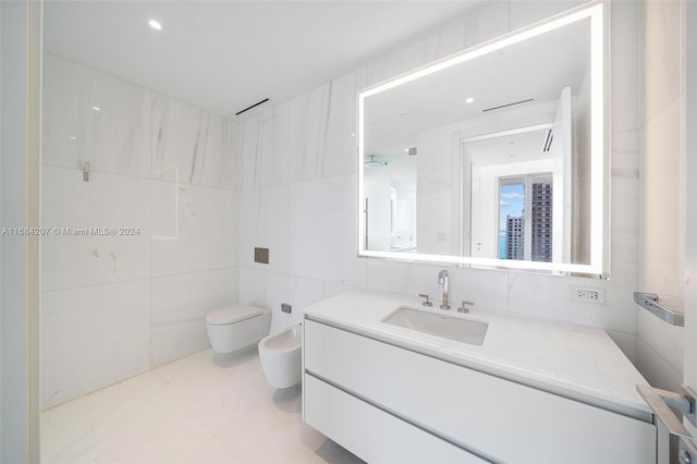 bathroom featuring toilet, tile walls, vanity, a bidet, and tile patterned flooring